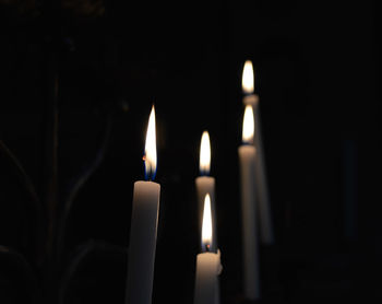 Close-up of illuminated candles in darkroom