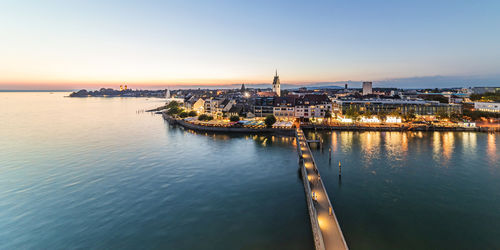 Germany, baden-wurttemberg, friedrichshafen, panoramic view of waterfront of city on shore of lake bodensee at dawn