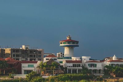 Lighthouse in city against clear sky