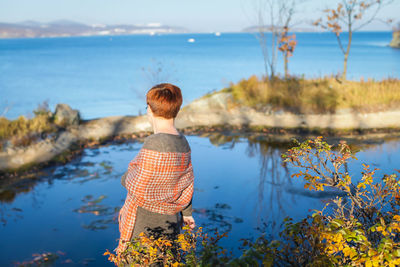 Rear view of woman looking at lake against sky