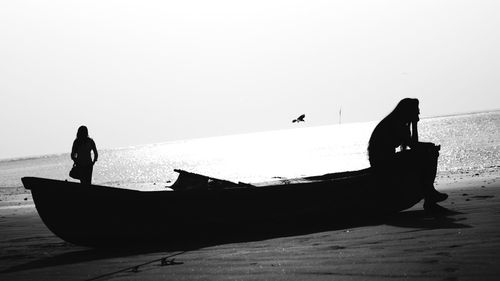 Silhouette woman and boat at beach