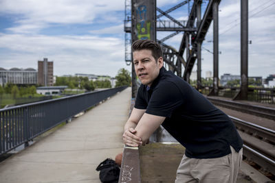 Portrait of young man standing on bridge