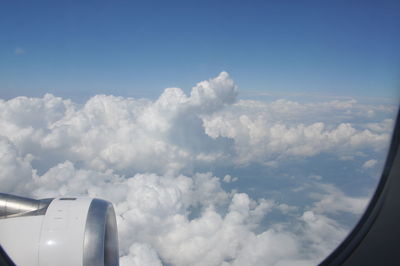 Cropped image of airplane wing over clouds