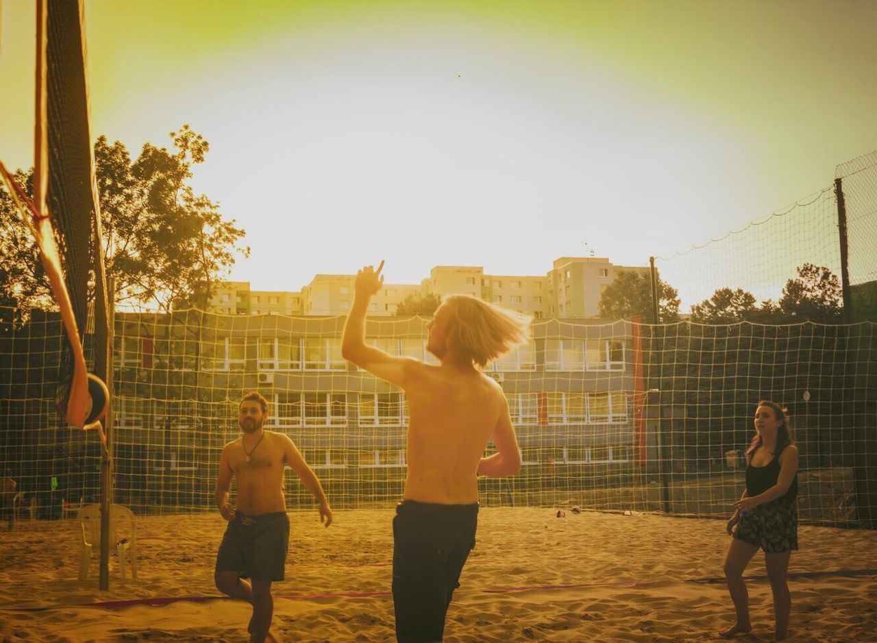 BOYS PLAYING SOCCER ON FIELD AGAINST SKY