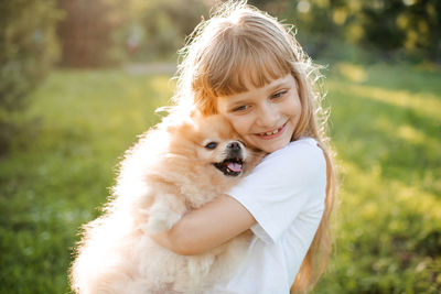 Close-up of girl embracing dog at lawn