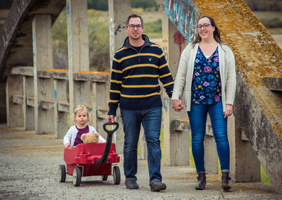 Portrait of a smiling young couple with toddler in wagon