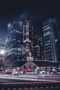 Illuminated city by buildings against sky at night