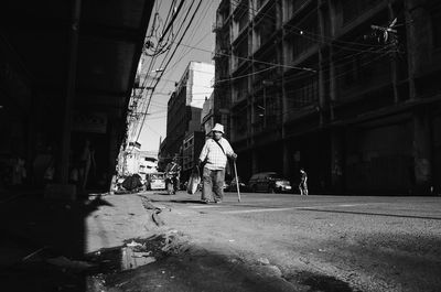Man walking on road amidst buildings in city