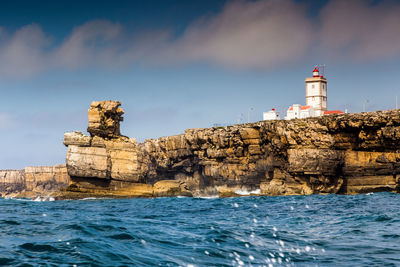 Lighthouse by sea against buildings