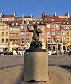 Statue by fountain in city against sky