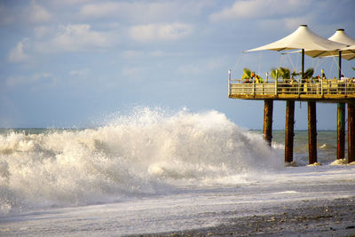 Scenic view of sea waves splashing on shore against sky