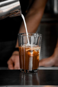 Close-up of hand pouring drink in glass