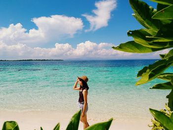 Woman standing at beach against sky