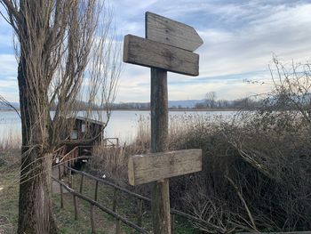 Wooden posts on field by lake against sky