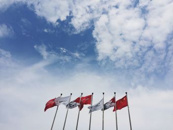 Low angle view of flags against cloudy sky