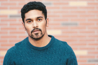 Close-up portrait of young man against brick wall