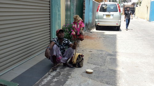 Man holding monkey while crouching on street