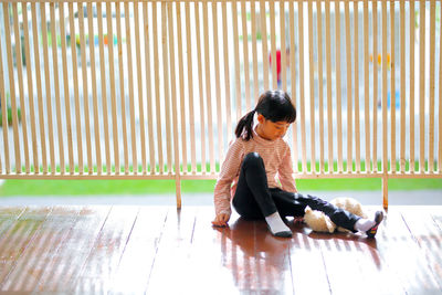 Side view of boy sitting on wooden floor