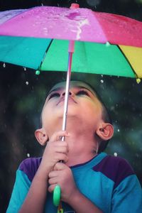 Portrait of boy holding wet umbrella