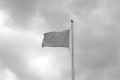Low angle view of waving flag against cloudy sky