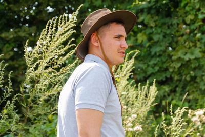 Male in hat. portrait of smiling farmer with green grass and trees nature in background. young man 