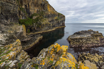 Rock formations by sea against sky