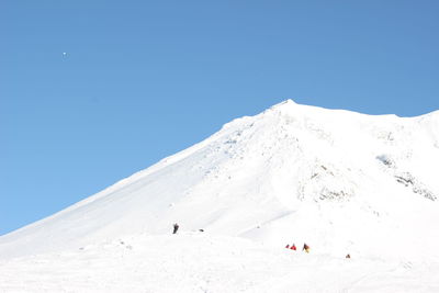 People on snowcapped mountain against clear blue sky