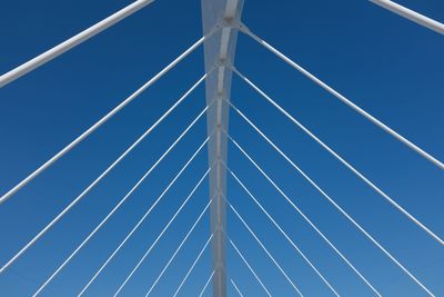 Low angle view of suspension bridge against blue sky