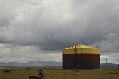 Building on field against cloudy sky