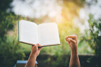 Close-up of person holding book while clenching fist