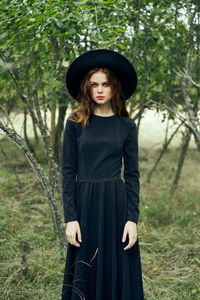 Portrait of young woman wearing hat standing on field