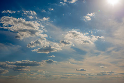 Low angle view of sunlight streaming through clouds