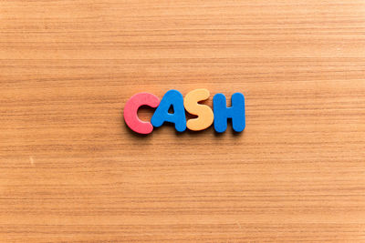 High angle view of colorful cash text on wooden table