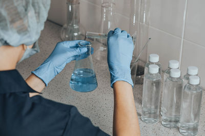 Woman in protective cap in laboratory checks water quality,  glass tube in lab