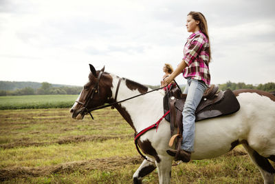 Side view of cowgirls riding on horse