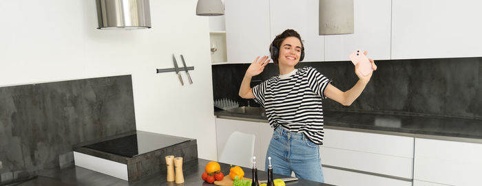 Full length of young woman standing against wall