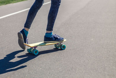 Low section of woman skateboarding on road