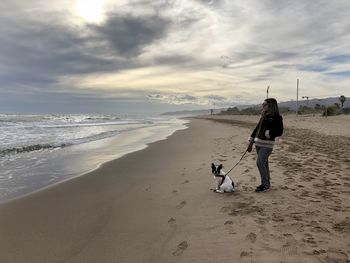 Woman with dog standing at beach