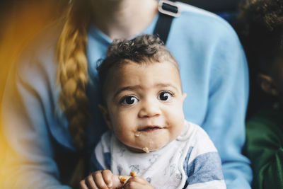 Close-up of toddler having food while sitting with mother in bus