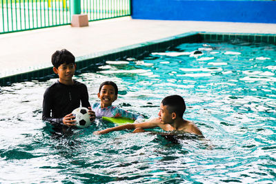 Full length of siblings and family swimming in pool
