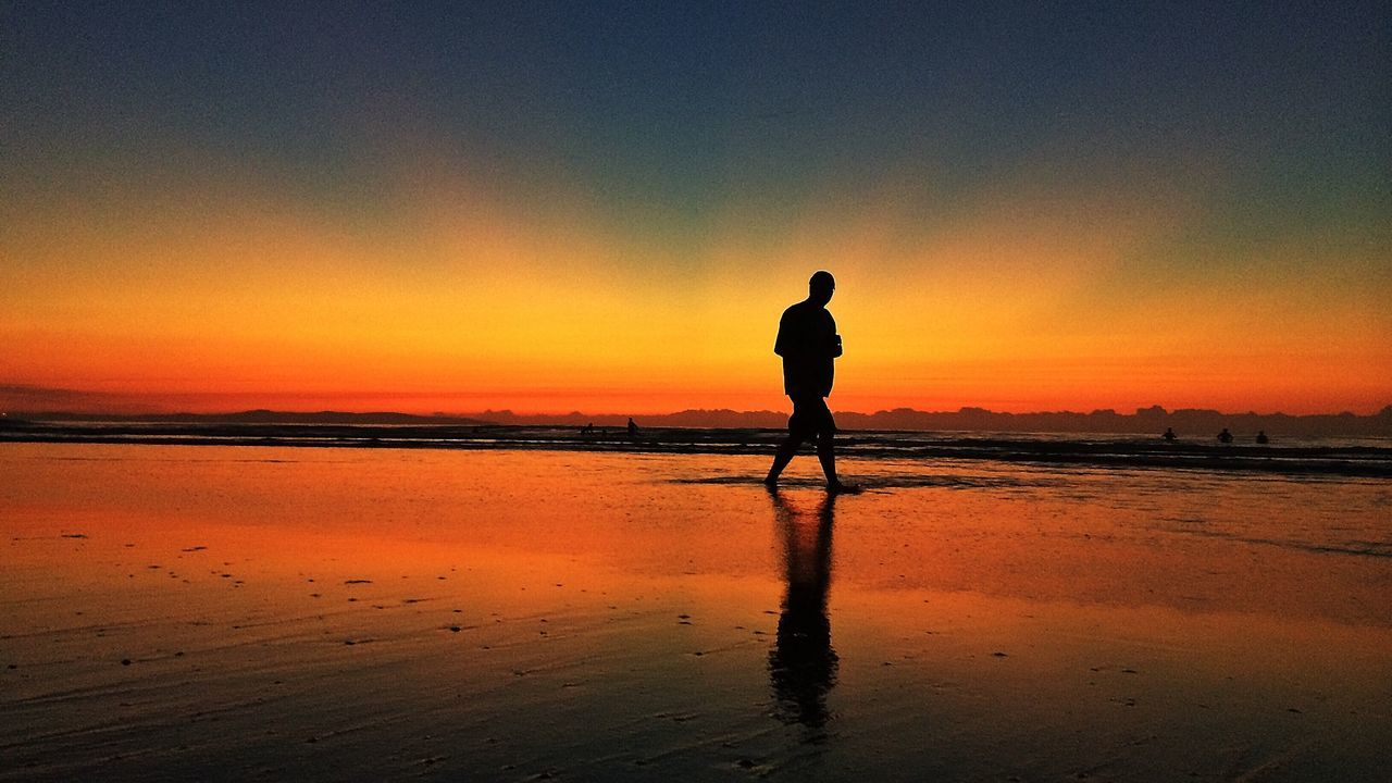 sunset, beach, water, silhouette, sea, shore, orange color, full length, leisure activity, lifestyles, scenics, standing, tranquil scene, reflection, horizon over water, beauty in nature, tranquility, sky