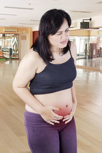 Woman with stomach ache standing in gym