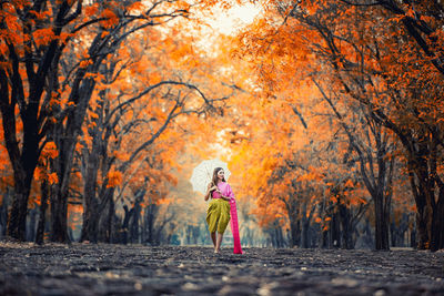 Full length of woman standing in forest during autumn