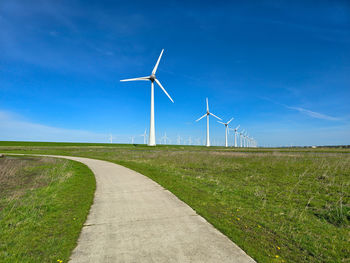 Windmills on field against sky