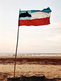 Red flag on beach against sky