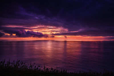 Scenic view of sea against dramatic sky during sunset