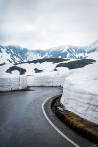 Road by snowcapped mountains against sky