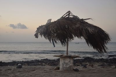 Built structure on beach against sky during sunset