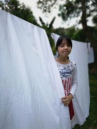 Portrait of girl standing by clothes drying on clothesline