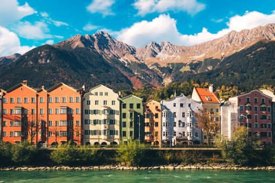 Houses by river and buildings against sky